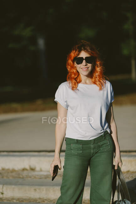 Очаровательная женщина с рыжими волосами, смеющаяся с закрытыми глазами на городской улице. — стоковое фото