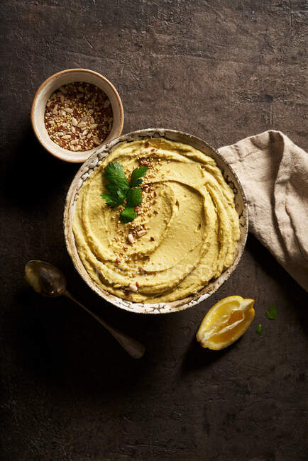 Top view bowl of delicious homemade hummus served on table with slice of lemon and chopped nuts — Stock Photo