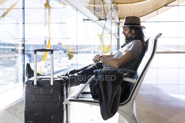 O tipo de chapéu no aeroporto, na sala de espera, à espera do voo. — Fotografia de Stock