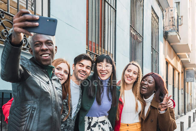 Maschio afroamericano scattare selfie con smartphone in compagnia di amici multirazziali in piedi sulla strada insieme — Foto stock