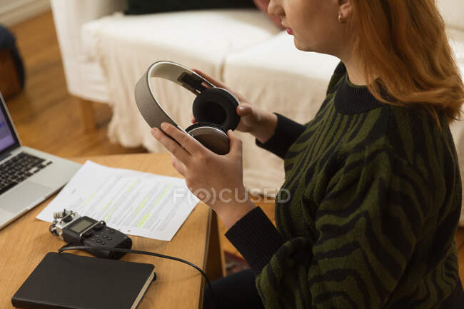 Вид сбоку на неузнаваемую женщину с наушниками, готовящуюся к записи подкаста дома — стоковое фото