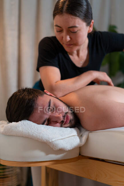 Female therapist doing Thai massage for male customer lying on table in spa salon — Stock Photo