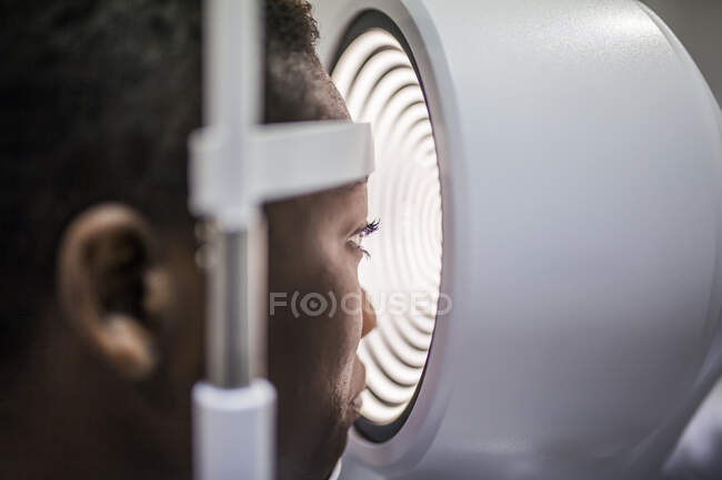 Mulher negra em gabinete de optometria durante o estudo da visão usando um topógrafo de córnea moderna — Fotografia de Stock