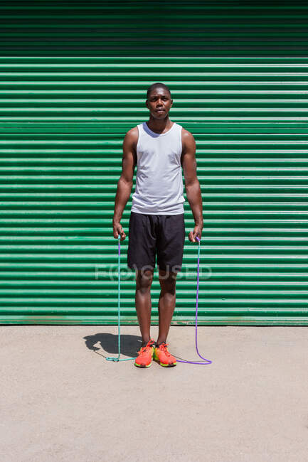 Focado afro-americano atleta masculino pulando corda durante o treino cardio no dia ensolarado na cidade — Fotografia de Stock