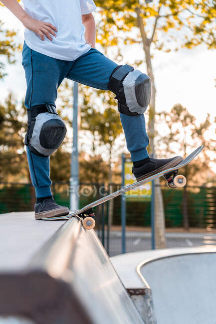 Урожай подросток фигурист стоя на скейтборде и готовится к показу трюк на рампе в скейт-парке — стоковое фото