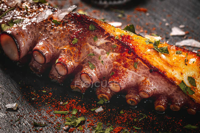 Du dessus délicieux tentacule de poulpe grillé servi avec des épices sur une planche de bois — Photo de stock
