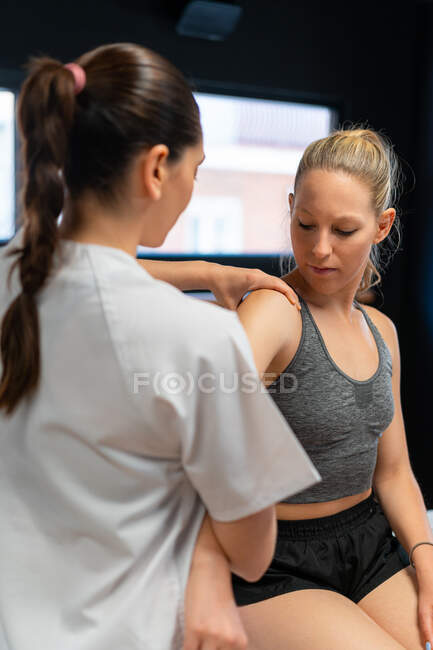 Female osteopath fitting shoulder join of patient in pain during physiotherapy session — Stock Photo