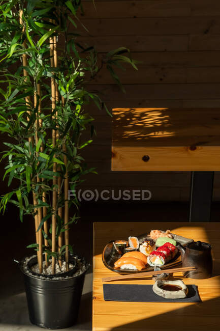 Assiette avec assortiment de rouleaux de sushi servis sur table avec baguettes et sauce soja au restaurant japonais — Photo de stock