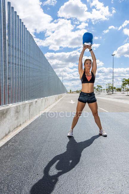 Young woman, training with the kettlebell outdoors, front view — Stock Photo