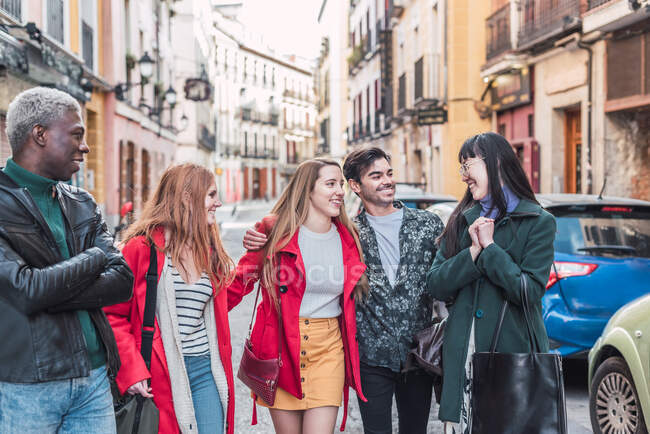 Компания счастливых многорасовых друзей в стильной одежде, гуляющих вместе на городской улице в выходные дни — стоковое фото
