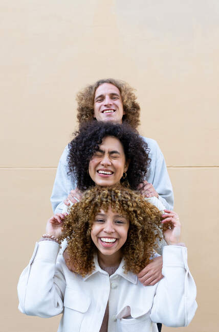 Diverso hombre y mujeres de pie uno detrás del otro mostrando cabezas con el pelo rizado y riendo - foto de stock