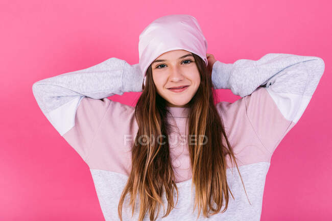 Contenida adolescente en traje casual y pañuelo para la cabeza para el concepto de cáncer demostrando brazos fuertes mientras mira a la cámara con sonrisa dentada - foto de stock