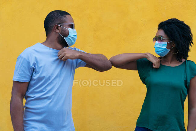 Couple noir avec masque saluant les uns les autres avec des coudes — Photo de stock
