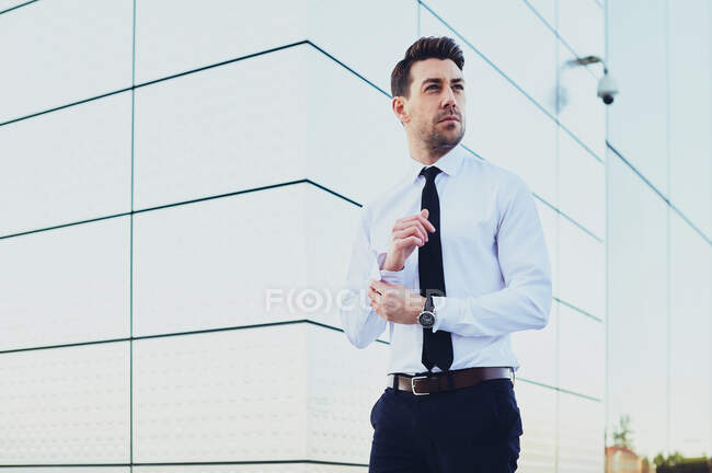 Homme entrepreneur en tenue formelle avec montre-bracelet regardant loin en ville — Photo de stock