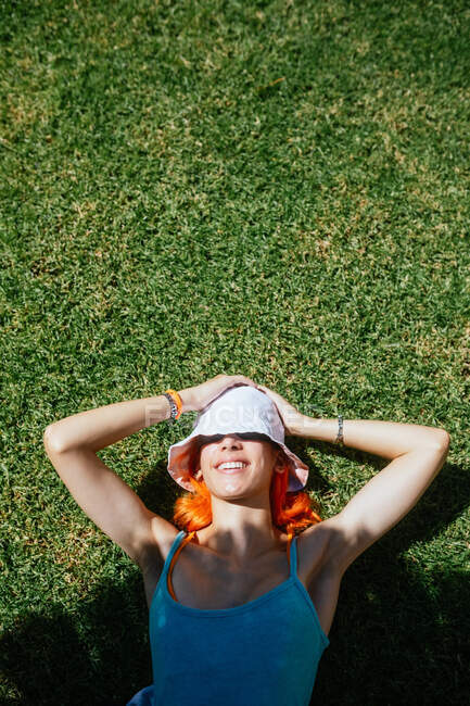 Вид зверху молода весела руда жінка лежить на траві в сонячний літній день — стокове фото