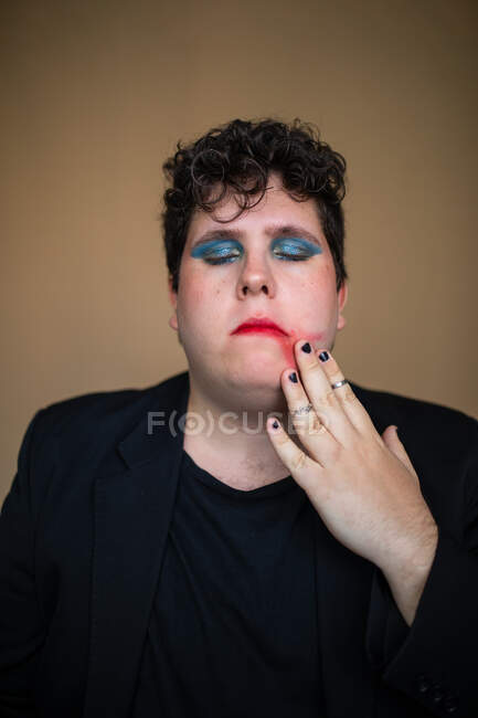Sensuale maschio transgender in sovrappeso con trucco luminoso toccare le labbra rosse — Foto stock