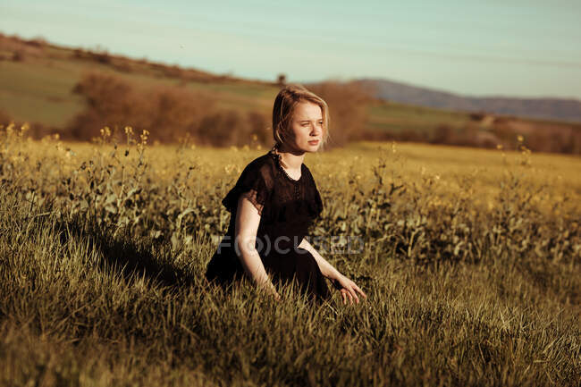 Ritratto di una bella giovane donna con in campagna distogliendo lo sguardo tra i fiori — Foto stock
