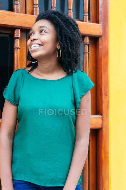 Красива і весела чорна жінка в хорошому настрої стоїть на міській вулиці. Дуже молода жінка зовні з посмішкою на обличчі, концепцією емоцій . — стокове фото