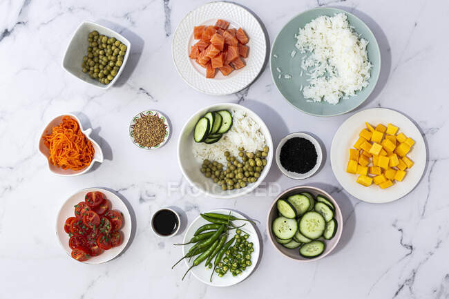 Vue de dessus de divers ingrédients frais pour la préparation traditionnelle de poke oriental placés sur une table en marbre — Photo de stock