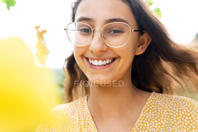 Снизу восторженная женщина в платье, стоящая в парке и смотрящая в камеру летом — стоковое фото