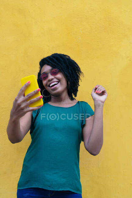 Retrato de una joven africana riendo con un smartphone al aire libre - foto de stock