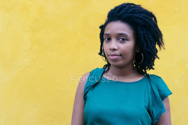 Портрет молодої чорної жінки з афро зачіскою, що спирається на стіну — стокове фото
