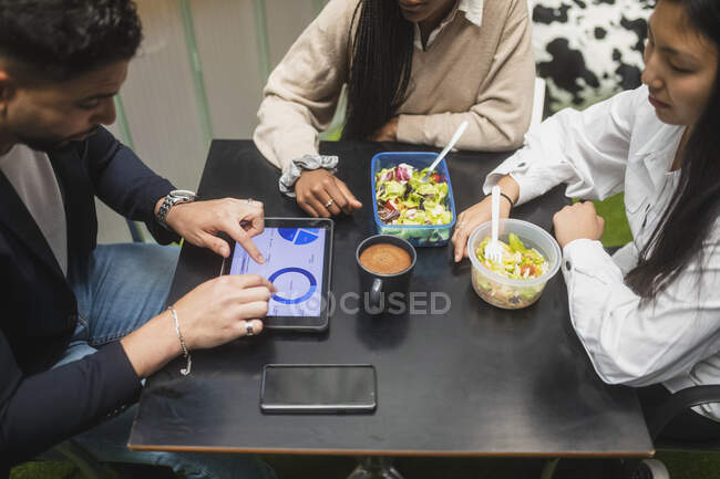 From above of crop multiracial coworkers sitting at table and having lunch during break in office — Stock Photo