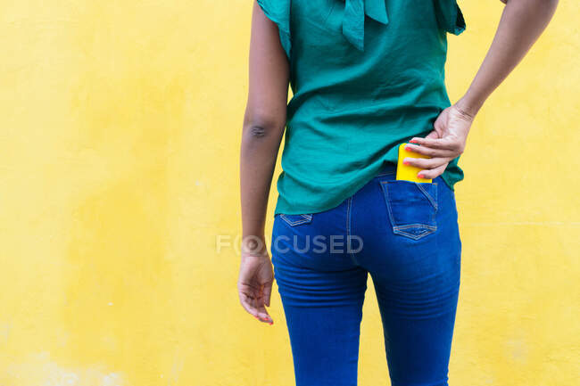 Jovem mulher em suas costas mantendo o smartphone em seus jeans. — Fotografia de Stock