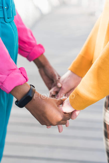 Crop coppia multietnica irriconoscibile di femmine lesbiche che si tengono per mano in città — Foto stock