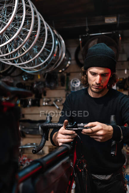 Serious mâle mécanicien guidon de fixation de vélo tout en travaillant dans l'atelier de réparation — Photo de stock