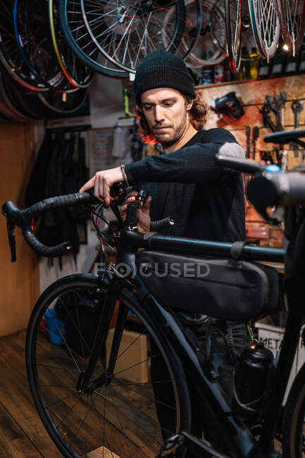 Serious male mechanic fixing handlebar of bicycle while working in repair service workshop — Stock Photo