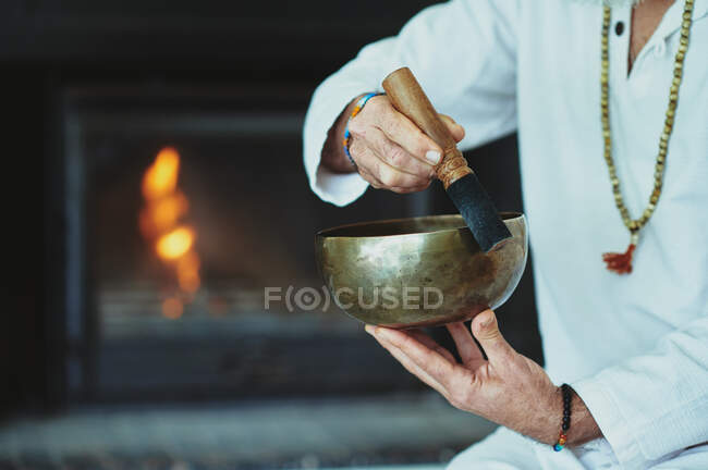 Crop man jugando al tazón de canto con el delantero de madera durante la práctica espiritual - foto de stock