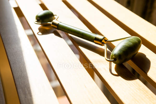 Von oben Jade-Walze für Wellness-Behandlung auf Holzbank zu Hause platziert — Stockfoto