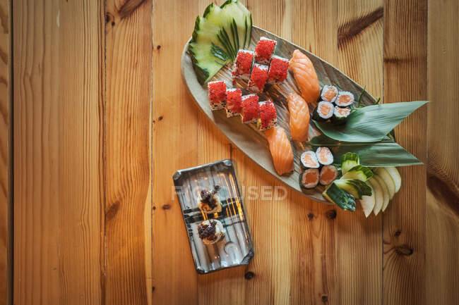 Des sushis gunkan et des rouleaux Uramaki servis sur des assiettes sur une table en bois dans un restaurant japonais — Photo de stock