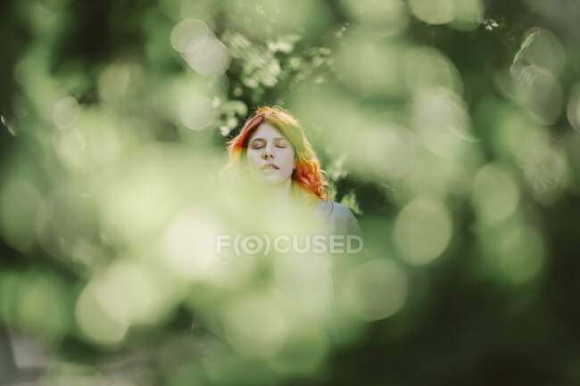 Мечтательная рыжая женщина отдыхает в зеленом парке и наслаждается летними выходными с закрытыми глазами — стоковое фото