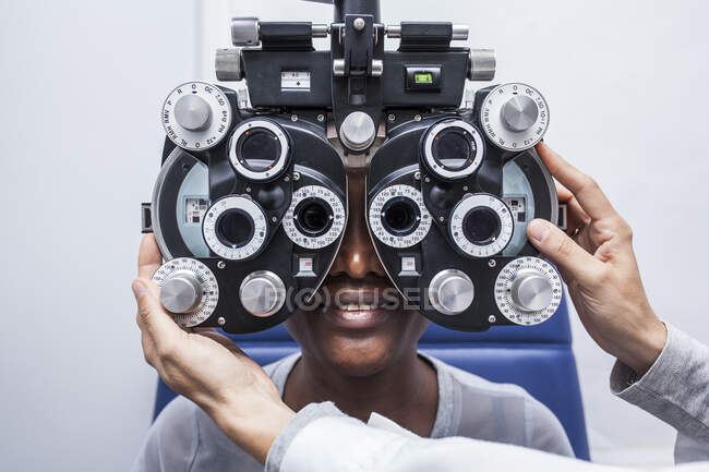 Оптометрист налаштування обладнання оптометрії під час вивчення зору чорної жінки — стокове фото