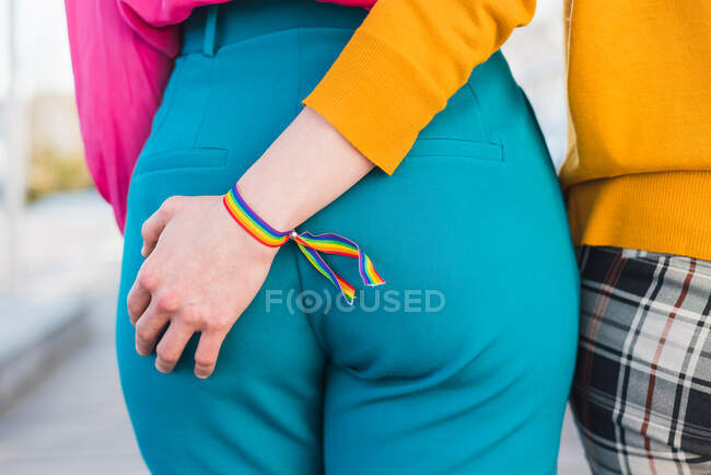 Vue arrière du couple multiracial anonyme recadré de femmes homosexuelles se tenant la main et marchant le long du pont en ville pendant la promenade estivale — Photo de stock