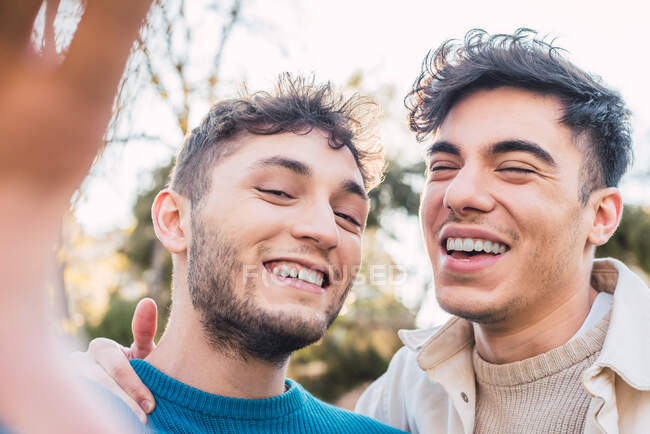 Positives homosexuelles Paar macht Selbstporträt und amüsiert sich am Wochenende im Park — Stockfoto