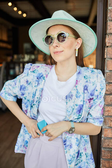 Smiling young female in stylish apparel with cellphone in cafeteria with lamps — Stock Photo