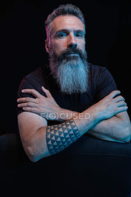 Handsome mature male with gray beard on black background in studio looking at camera — Stock Photo