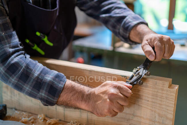 Ernte unkenntlich männliche Tischler glätten Holzplanke mit professioneller Holzbearbeitung Messer Sprecher haben manuelle Hobelmaschine in der Werkstatt — Stockfoto