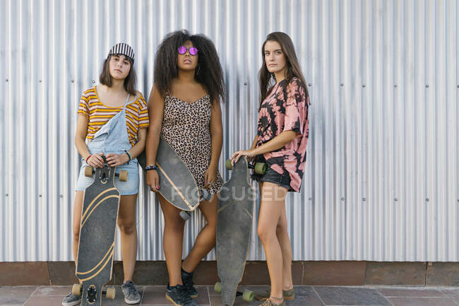 Drei schöne junge Frauen unterschiedlicher Rassen mit ihren langen Brettern schauen in die Kamera — Stockfoto