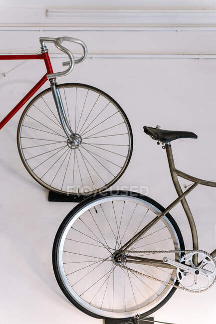 Old bikes hanging on background of white wall in repair service workshop at daytime — Stock Photo