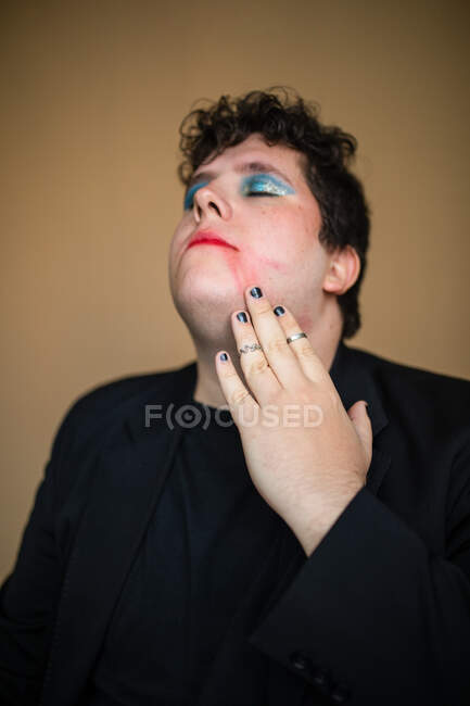 Sensual overweight transgender male with bright makeup touching red lips — Stock Photo