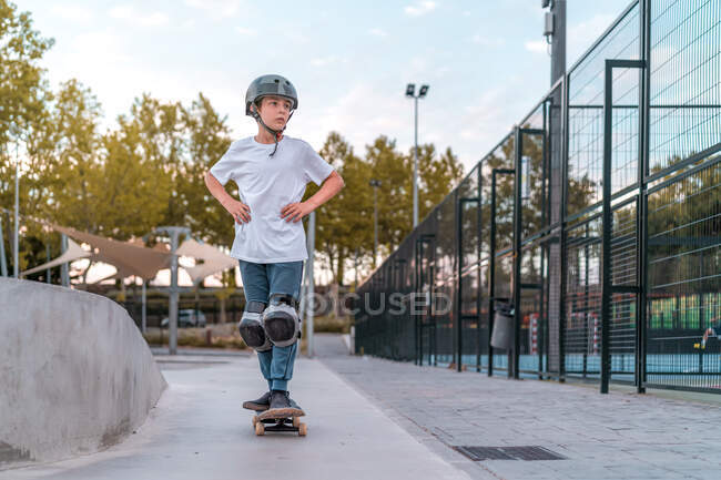 Teenager-Skater in Schutzausrüstung fährt Skateboard am Wochenende im Skatepark und schaut weg — Stockfoto