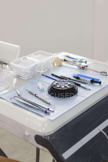 Высокий угол расположения различных стоматологических инструментов возле шпона на столе для процедуры в профессиональной клинике — стоковое фото