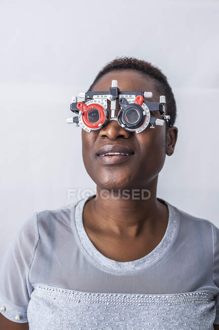 Heureuse femme noire dans une armoire d'optométrie pendant l'étude de la vue — Photo de stock
