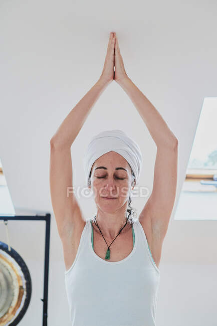Donna in piedi in posa Vrksasana durante la pratica dello yoga su moquette morbida e occhi chiusi in camera di casa — Foto stock