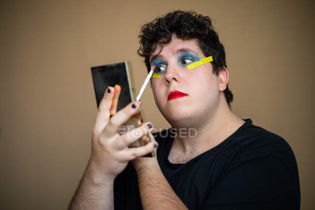 Applying bright makeup on eyelids of queer male — Stock Photo