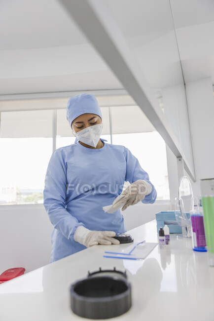Female medic in blue uniform and respiratory mask at table with small bottles in hospital — Stock Photo